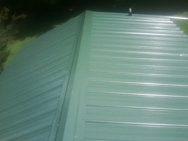 New green metal panels meeting at the ridge of a roof — Flat Roof Repair work by our crew in Hoodsport