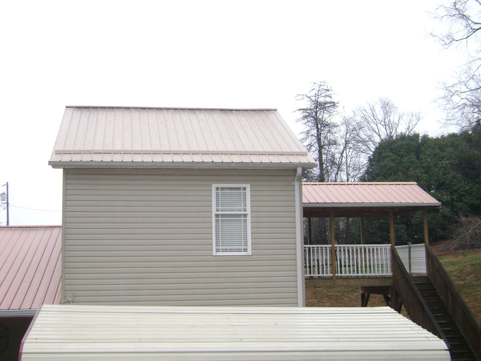 Tan metal roofs on a two story addition and attached porch, from a Roof Replacement job in Hoodsport