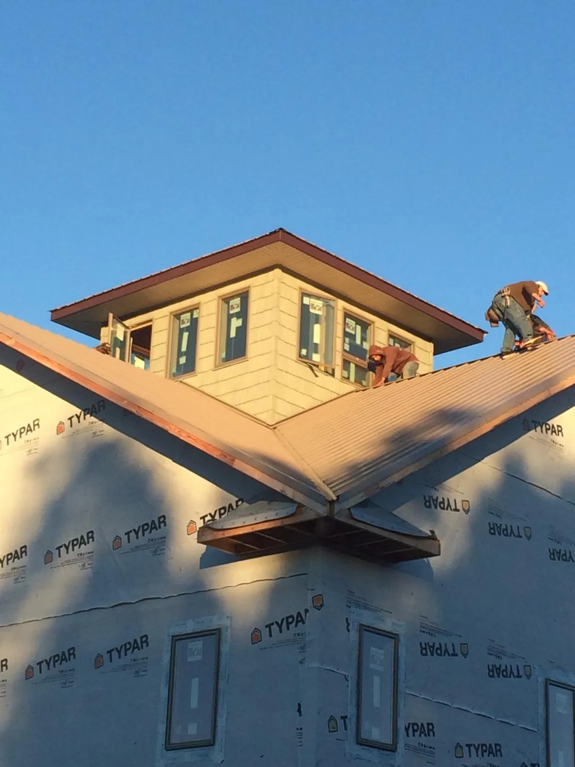 Roofers working around a rooftop cupola on a new metal roof at sunset — Roof Waterproofing in Hoodsport by Roofing Brothers